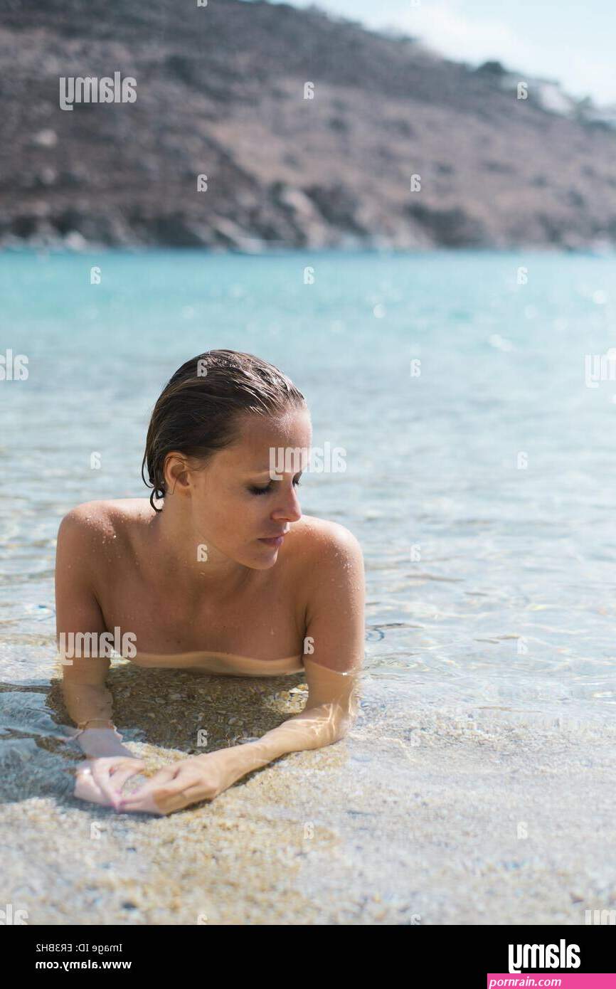 Naked Woman lying in shallows on a beach Stock Photo