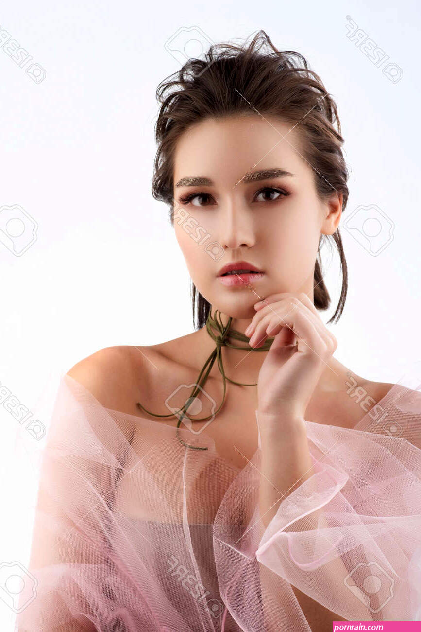Beautiful Young Big Breast Asian Girl Wearing A Pink Veil On Her Naked Shoulders And A Choker On Her Neck Sensually Touches Her Face And Neck. Isolated On White. Smooth Healthy Skin.