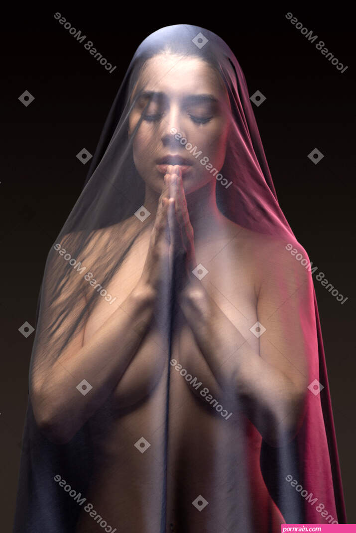 Foto de Sensual mujer joven desnuda rezando en velo oscuro