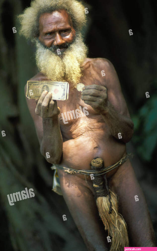 Old man in penis sheath belonging to local cargo cult holds up American banknotes and coins Tanna Island Vanuatu Stock Photo