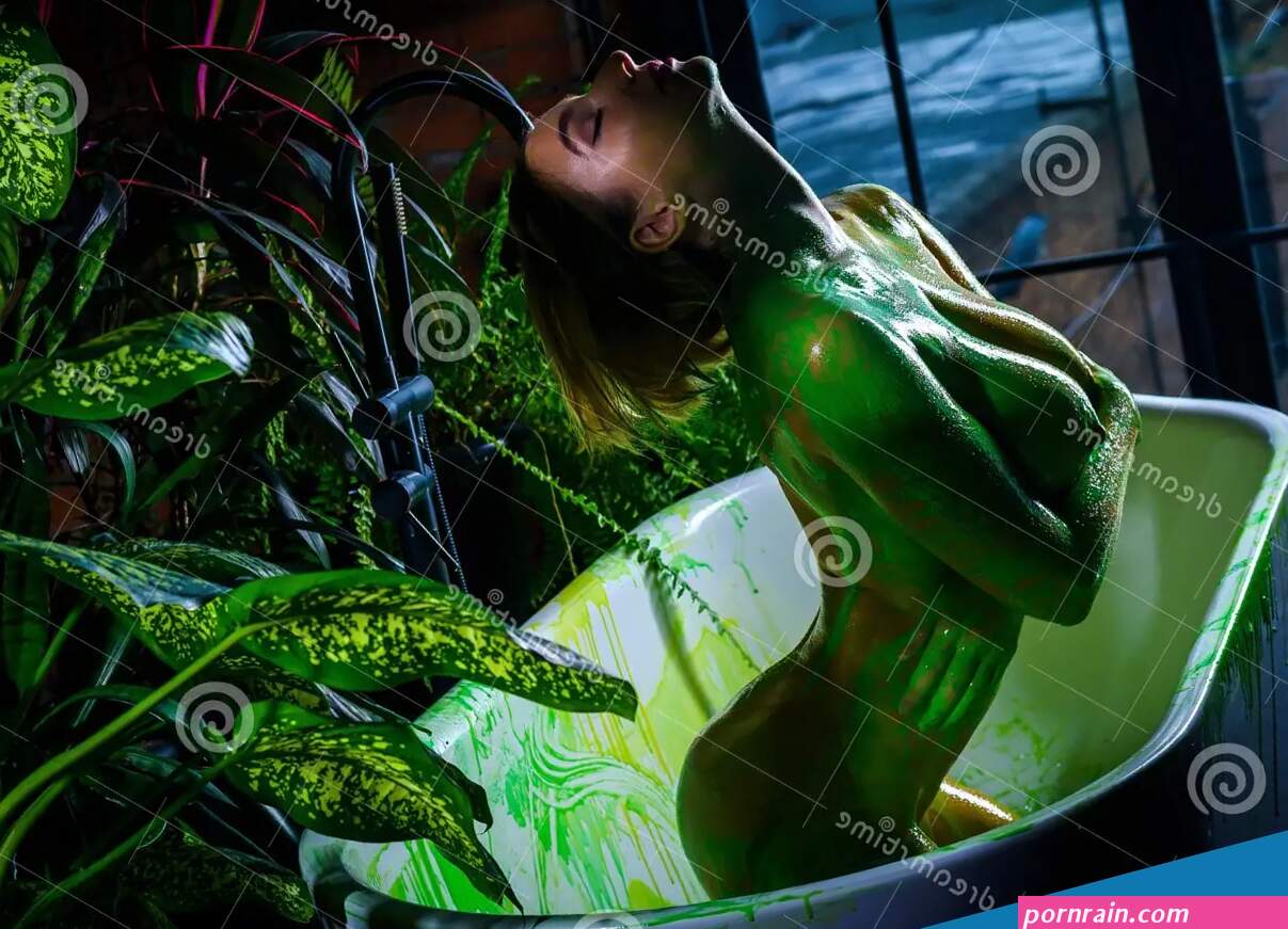 Beautiful European Woman with Very Big Breasts Takes a Bath. Green Paint Flows Down the Naked Body of a Girl in the Stock Image